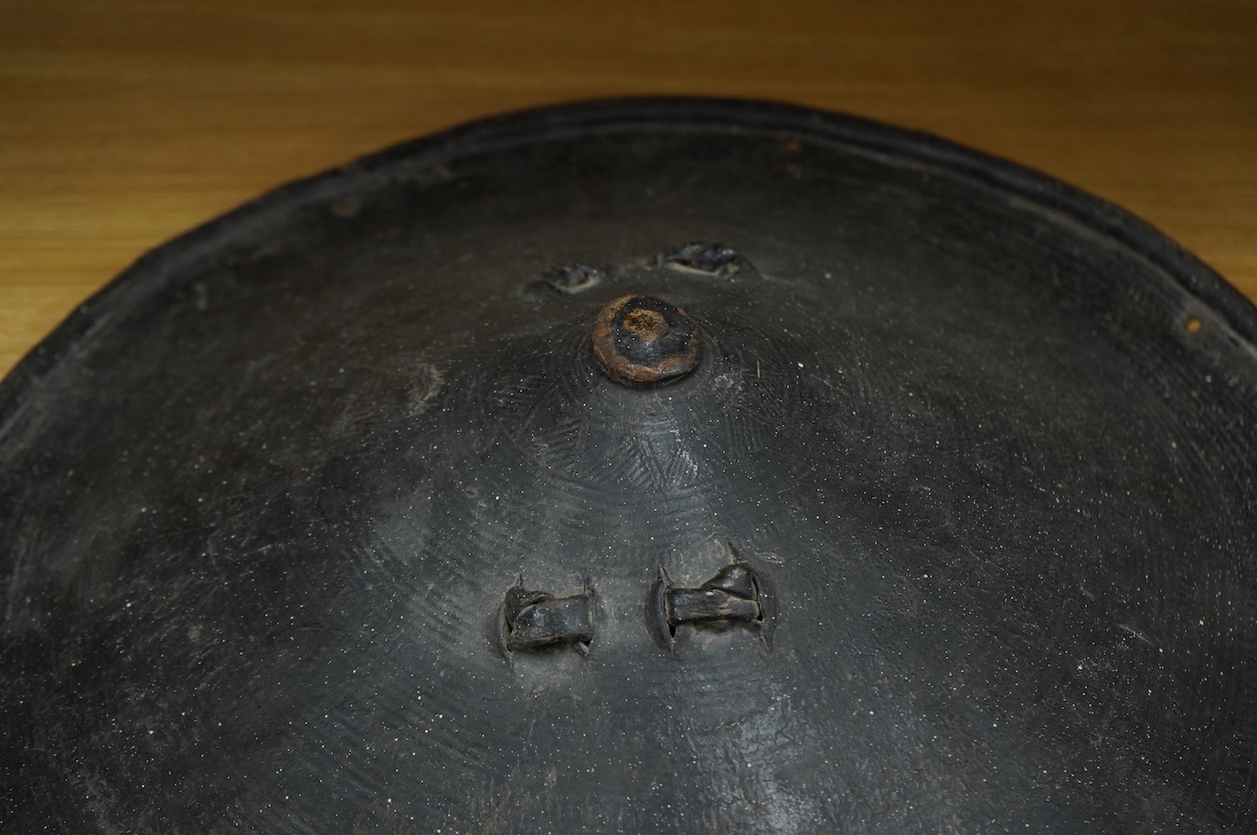 A 19th century Ethiopian/Somali leather shield, 56cm diameter, outside with incised geometric decoration rising to a point, reinforced brim, inside with woven leather handle. Condition - good.